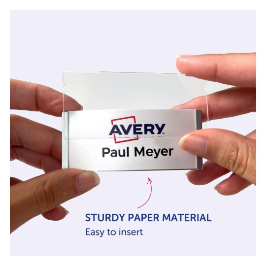 Bilden visar en person som håller en namnbricka med Avery-loggan och namnet "Paul Meyer" på den. Namnbrickan verkar vara lätt att sätta in i en hållare gjord av robust papper.