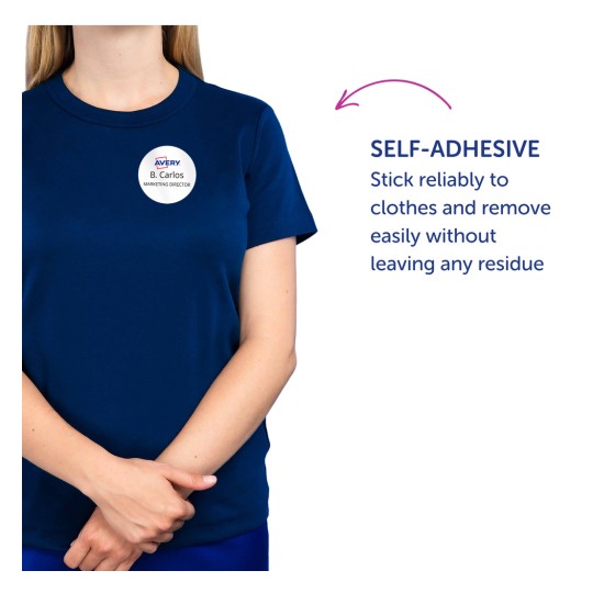 Bilden visar en person som bär en marinblå t-shirt med en självhäftande namnbricka som säger 'B. Carlos MARKETING DIRECTOR'. Texten till höger belyser den självhäftande funktionen och betonar dess pålitlighet och att den kan tas bort utan att lämna rester.