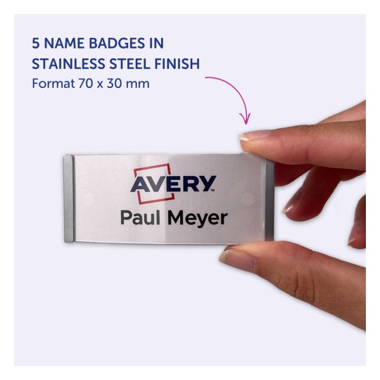 Bilden visar en person som håller ett namnbricka med texten 'Avery Paul Meyer.' Det anger att produkten är ett set med fem namnbricka i rostfritt stål-utförande, med måtten 70 x 30 mm.