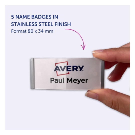 Bilden visar en hand som håller en namnbricka i rostfritt stål med texten 'Avery' och namnet 'Paul Meyer'. Den anger att det finns 5 namnskyltar i detta format, som mäter 80 x 34 mm.