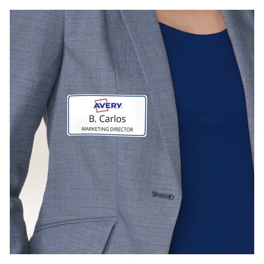 Bilden visar en namnskylt märkt 'B. Carlos, MARKNADSDIREKTÖR' fäst på en persons blazer. Namnskylten har logotypen för 'Avery'.