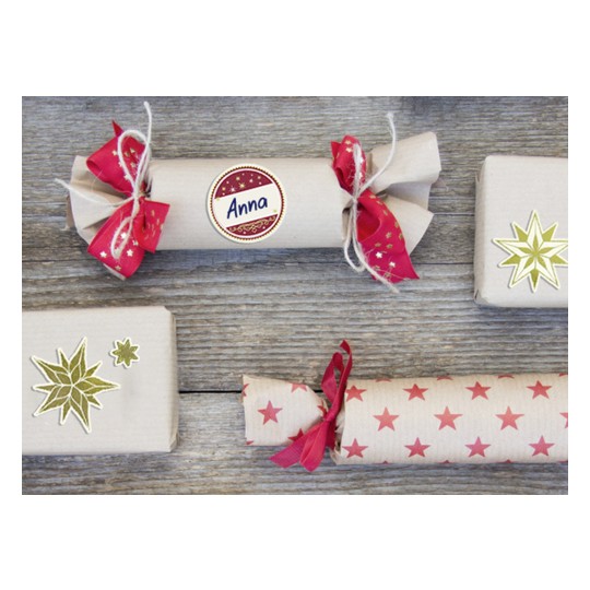 Bilden visar flera dekorerade presentpaket arrangerade på en träyta. Gåvorna är inslagna i kraftpapper med festliga band och klistermärken, vilket skapar en mysig, högtidlig känsla.