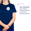 Bilden visar en person som bär en marinblå t-shirt med en självhäftande namnbricka som säger 'B. Carlos MARKETING DIRECTOR'. Texten till höger belyser den självhäftande funktionen och betonar dess pålitlighet och att den kan tas bort utan att lämna rester.