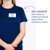 Bilden visar en person som bär en marinblå skjorta med en namnskylt som lyder 'B. Carlos, MARKNADSDIREKTÖR.' Skylten är självhäftande och det finns text som förklarar dess egenskaper.