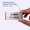 Bilden visar en hand som håller en namnbricka i rostfritt stål med texten 'Avery Paul Meyer' på. Det nämns att det finns 20 namnskyltar tillgängliga i en finish av rostfritt stål, med måtten 70 x 30 mm.