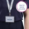 På bilden syns en person som bär en mörk skjorta och ett band med en ID-bricka som lyder 'MELINA DOPPER' och 'Designer.' Bandet har ett färgglatt blommönster. En textbubbla på bilden säger 'Perfekt för ID-BRICKSHÅLLARE.'