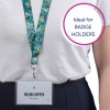 Bilden visar en person som bär ett nyckelband med en färgglad tropisk design. Ett ID-kort är fäst, som visar namnet 'Melina Doppler' och titeln 'Designer.' I bakgrunden finns en cirkulär text 'Ideal for BADGE HOLDERS.'