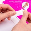 Bilden visar en persons händer som lossar ett manipuleringssäkert armband från ett ark. Bakgrunden har en ljusrosa färg, och en mindre infälld bild visar armbandet applicerat på en handled.