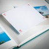 Bilden visar ett öppet fotoalbum med en tom sida redo för ett foto att läggas till. Albumet innehåller bilder av en strand och havslandskap, med den tomma sidan framträdande visad.