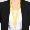 Bilden visar en person som bär en svart blazer över en vit skjorta, med ett ljust gult nyckelband som hänger runt halsen, vilket har en klämma fäst vid sig.